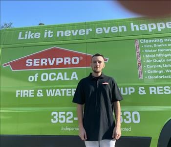Kevin standing in front of a green SERVPRO van