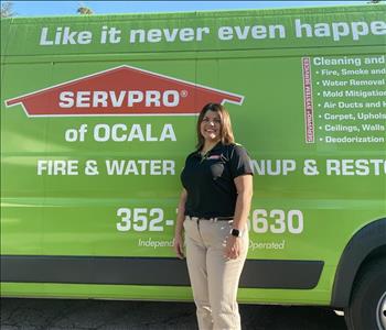 Addy standing in front of a green SERVPRO van