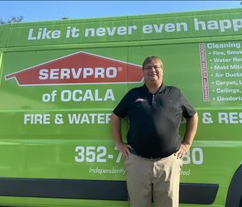 John standing in front of a green SERVPRO van