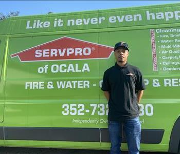 DeTavious in front of green SERVPRO vehicle