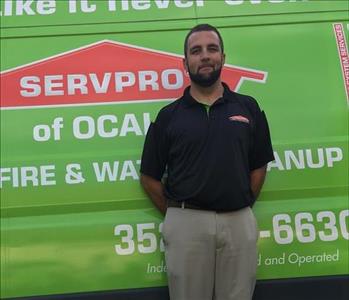 Jacob standing in front of a green SERVPRO van