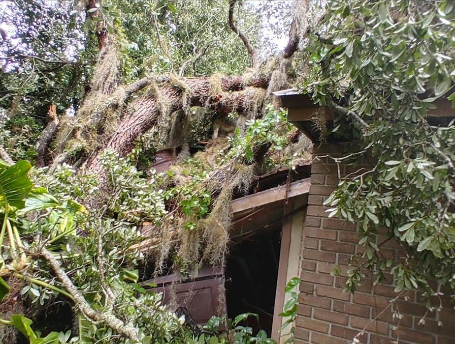 Large tree on top of a house roof from storm damage